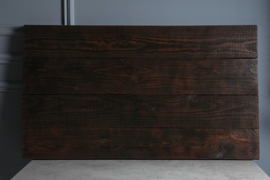 Photo of Dark wooden board on table near light grey wall