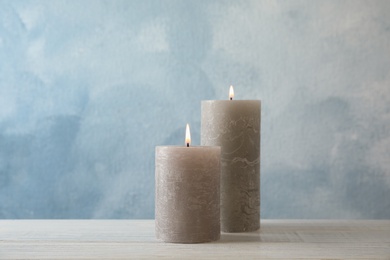 Burning candles on table against color background. Space for text