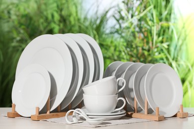 Photo of Set of clean dishware on white table against blurred background