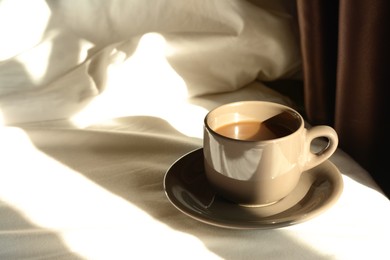 Photo of Cup of aromatic coffee on bed in morning, space for text