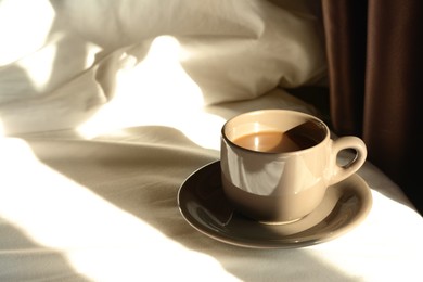 Cup of aromatic coffee on bed in morning, space for text