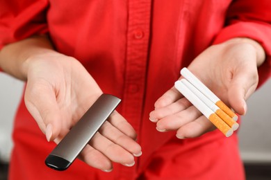 Woman with cigarettes and vaping device on light background, closeup. Smoking alternative