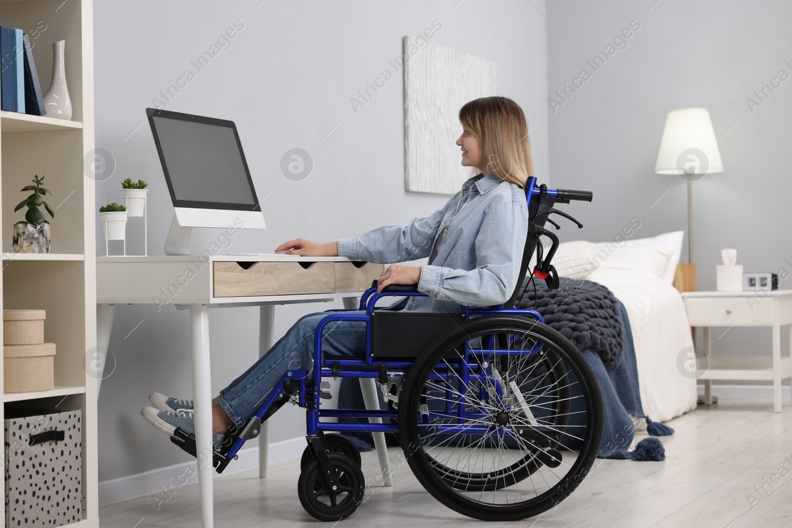 Photo of Woman in wheelchair using computer at table in home office