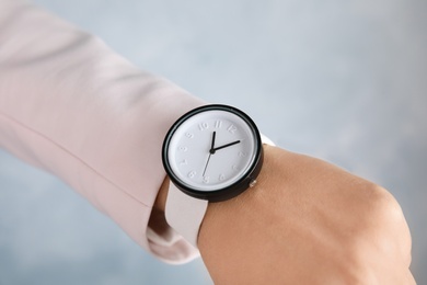 Businesswoman with stylish wrist watch on color background, closeup. Time management