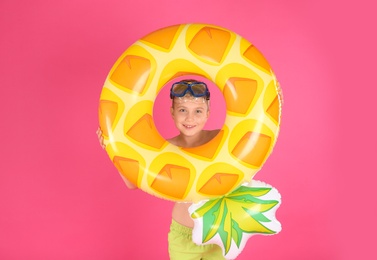 Photo of Cute little child in beachwear with bright inflatable ring on pink background