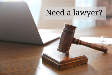 Text NEED A LAWYER? and judge gavel on wooden table indoors