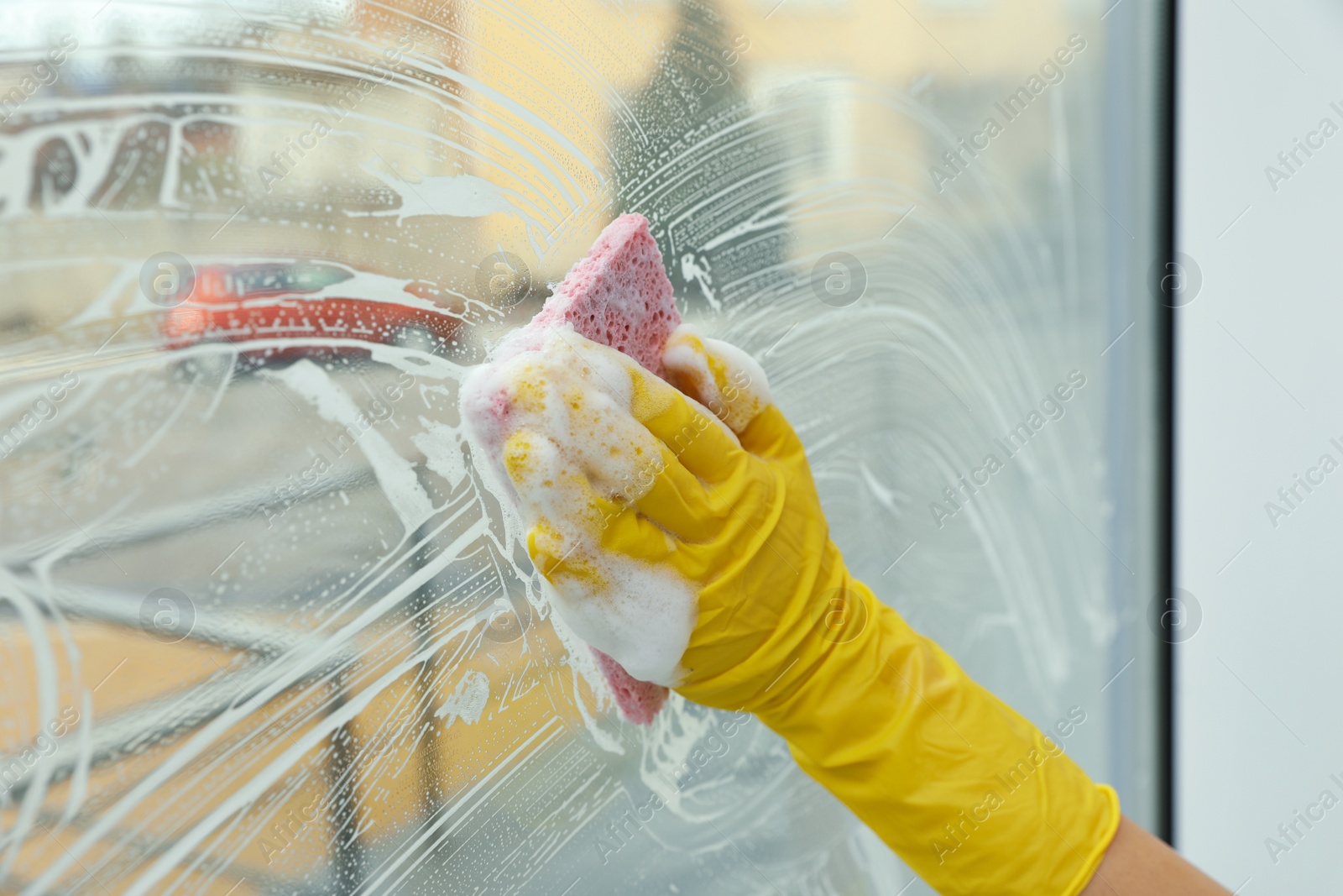 Photo of Woman cleaning window with sponge at home, closeup