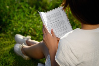 Woman reading book outdoors on sunny day, closeup