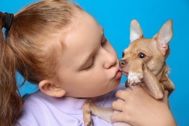 Photo of Little girl with her Chihuahua dog on light blue background, closeup. Childhood pet