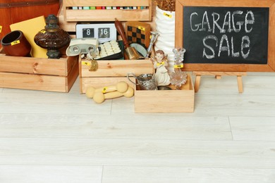 Photo of Sign Garage Sale written on blackboard and many different stuff on floor