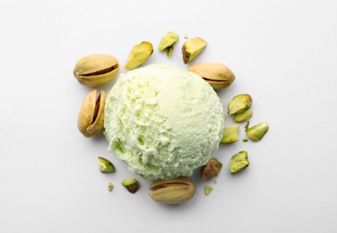 Scoop of delicious pistachio ice cream and nuts on white background, top view