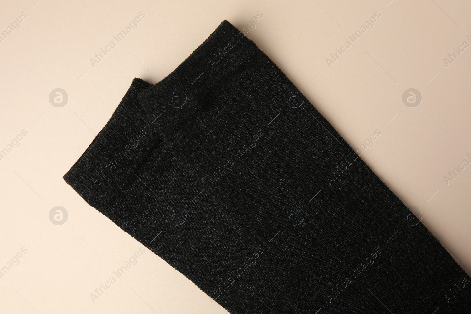 Photo of Black cloth with lint on beige background, top view. Before using fabric shaver