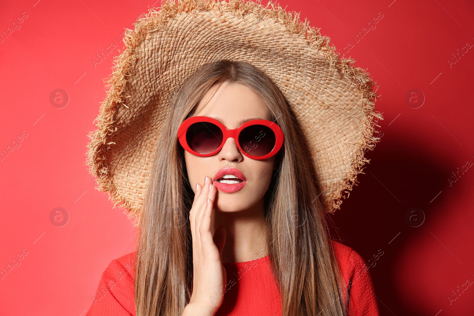 Photo of Young woman wearing stylish sunglasses and hat on red background