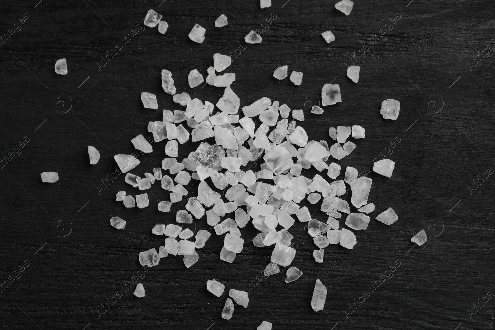 Photo of Natural sea salt on black table, flat lay