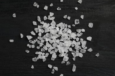 Photo of Natural sea salt on black table, flat lay