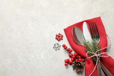 Photo of Cutlery set and festive decor on light grey table, flat lay with space for text. Christmas celebration
