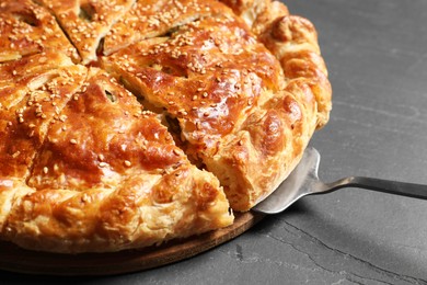 Photo of Cut delicious homemade pie and server on black table, closeup