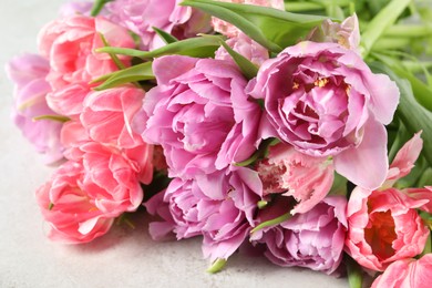 Photo of Beautiful bouquet of colorful tulip flowers on light table, closeup