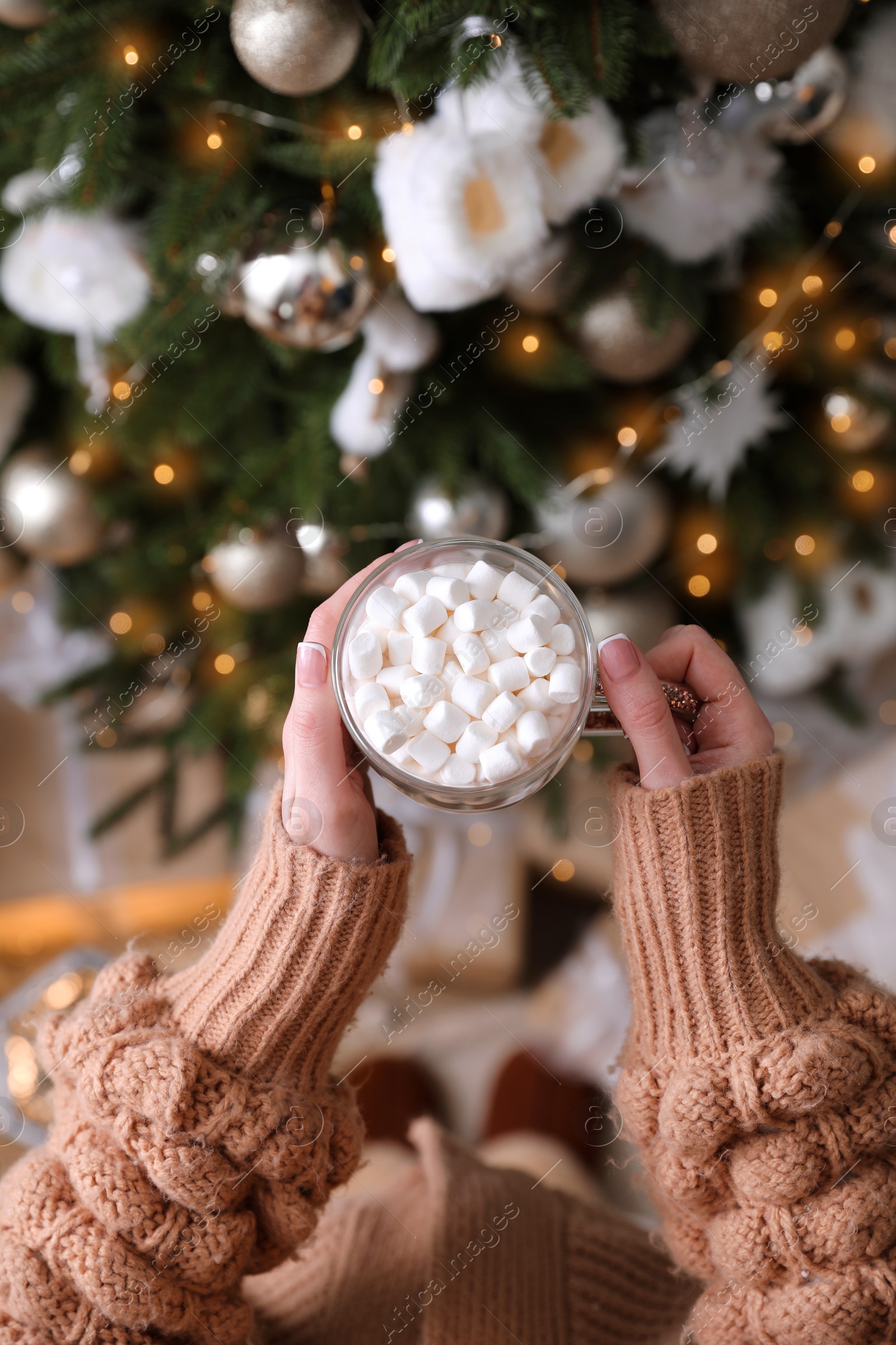 Photo of Woman with cup of delicious hot drink near Christmas tree at home, top view