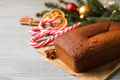 Delicious gingerbread cake and Christmas items on wooden table, space for text