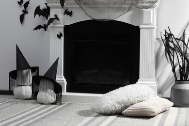 Beautiful black witch hats on pumpkins near fireplace indoors. Halloween celebration