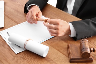 Photo of Male notary working with documents at wooden table, closeup