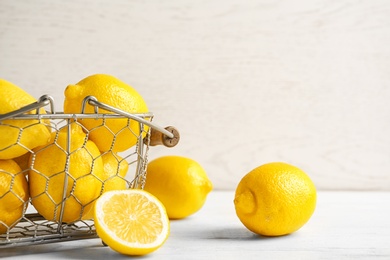 Photo of Basket with ripe lemons on table against light background