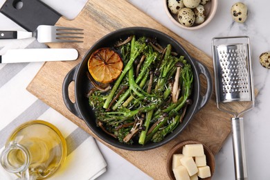Photo of Tasty cooked broccolini, mushrooms and lemon on white marble table, flat lay