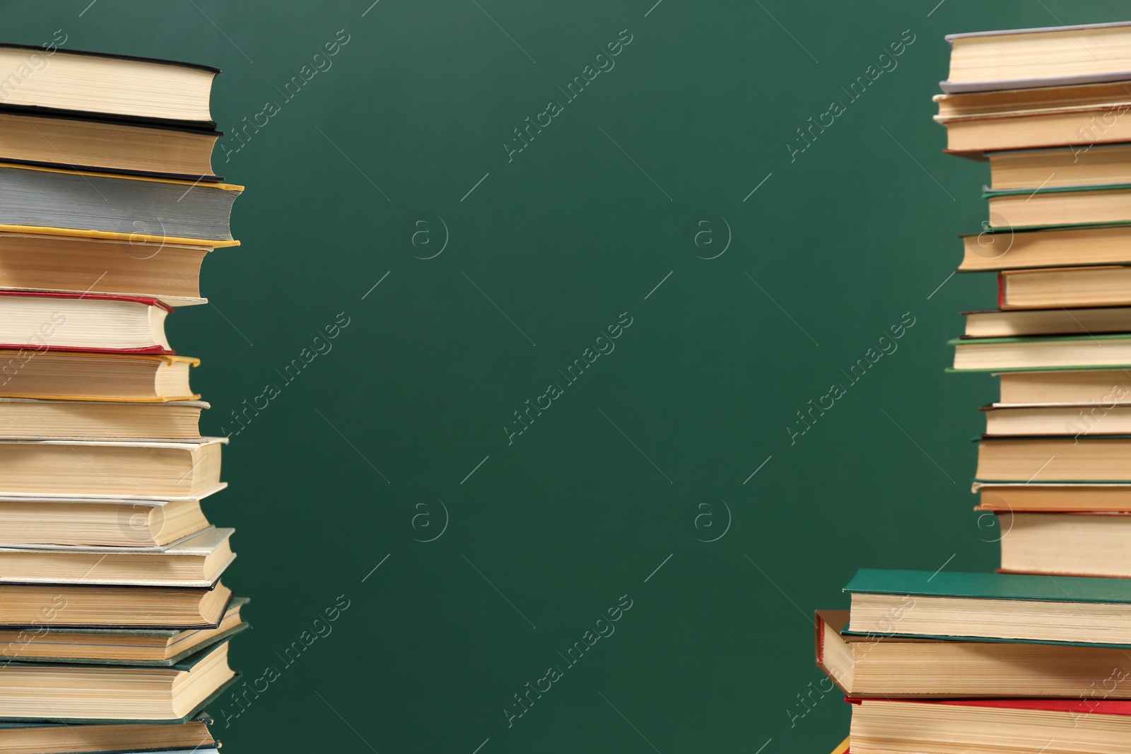 Photo of Many hardcover books near green chalkboard, space for text. Library material