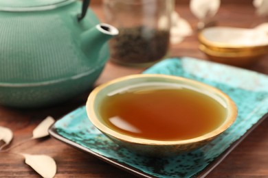Photo of Teapot and cup of freshly brewed tea on wooden table, closeup. Traditional ceremony