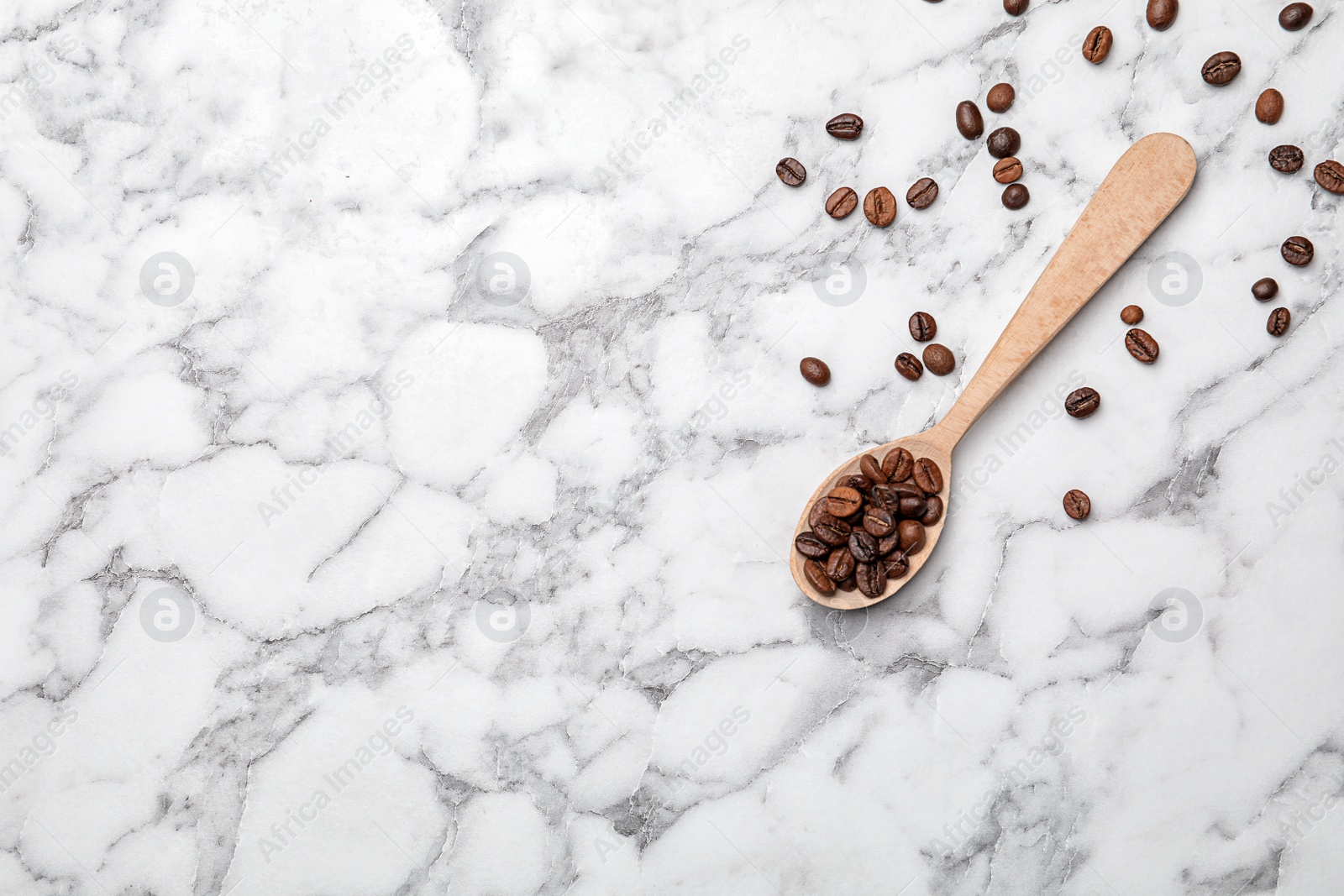 Photo of Spoon with coffee beans on marble background, top view