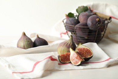 Tasty cut and whole figs on table with napkin