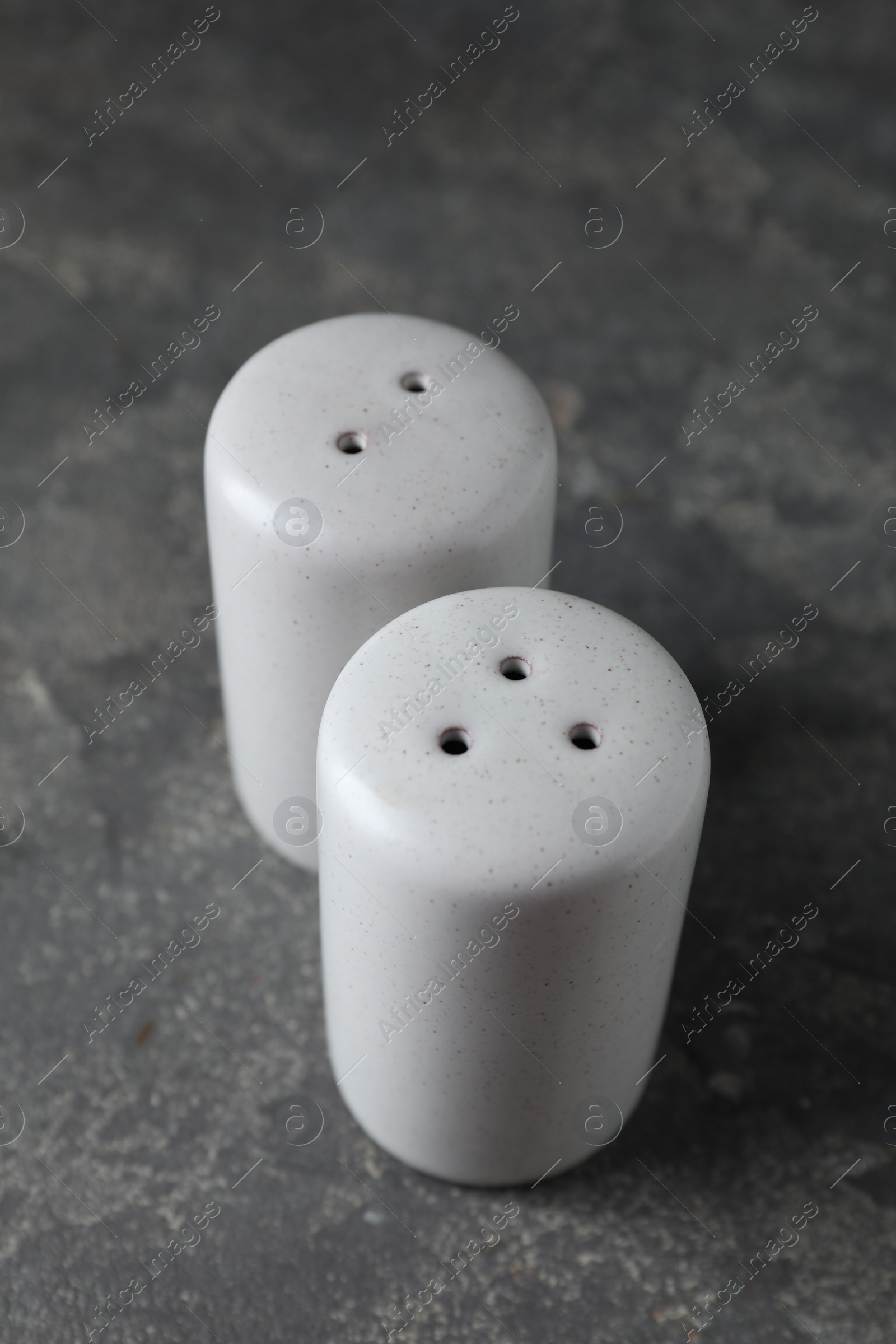 Photo of Salt and pepper shakers on dark textured table