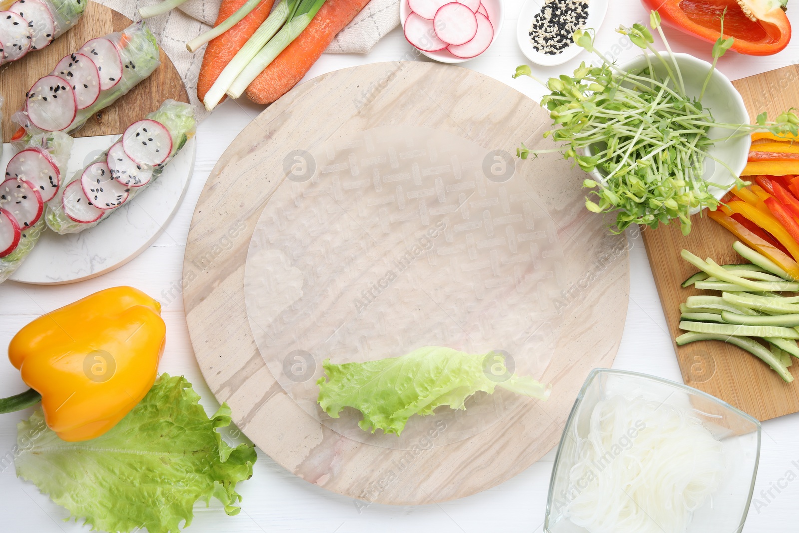 Photo of Rice paper and other ingredients for spring rolls on white wooden table, top view