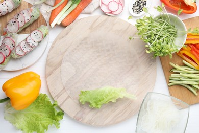 Rice paper and other ingredients for spring rolls on white wooden table, top view