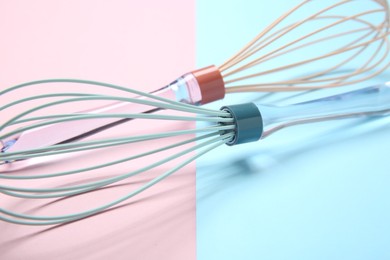 Photo of Two whisks on color background, closeup view