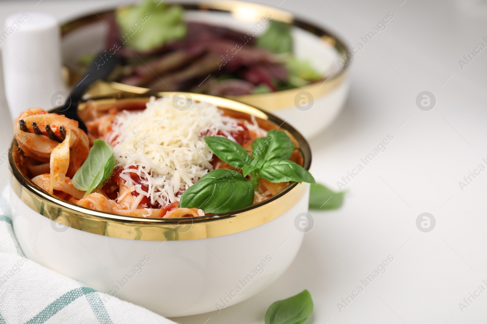 Photo of Delicious pasta with tomato sauce, basil and parmesan cheese on white table, closeup. Space for text