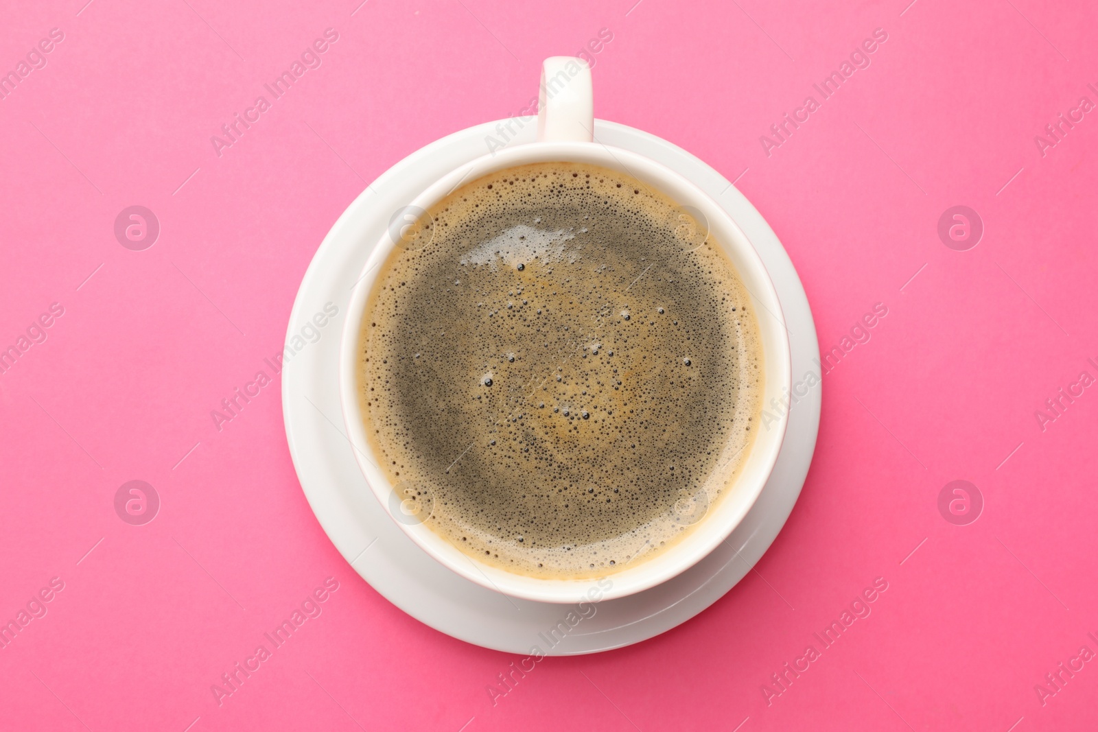 Photo of Fresh coffee in cup on pink background, top view