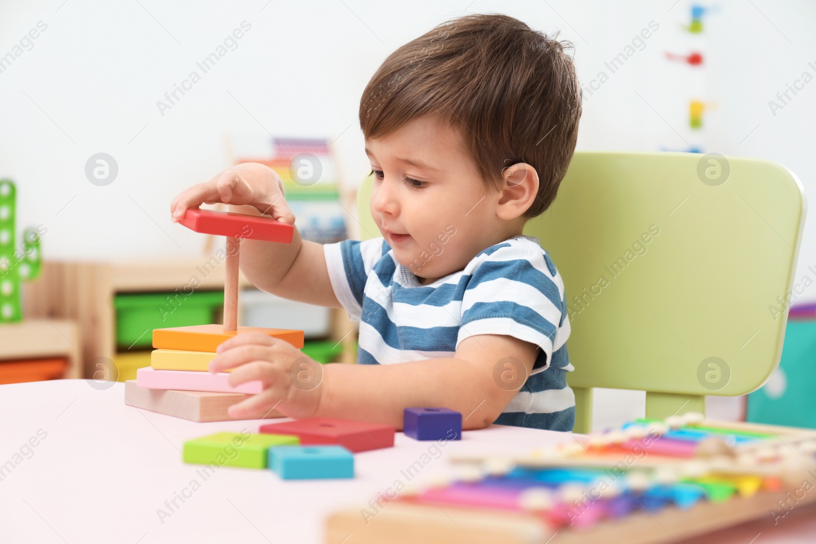 Photo of Little child playing with toy pyramid at table