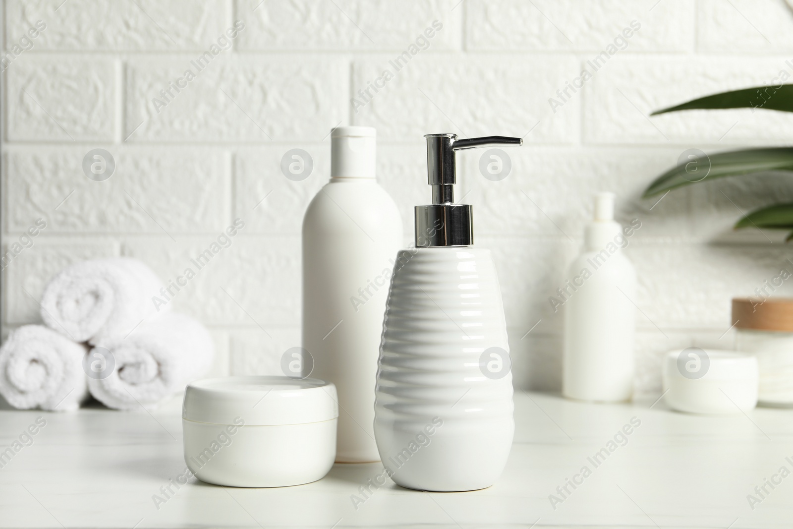 Photo of Different bath accessories and personal care products on white table near brick wall