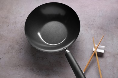 Empty iron wok and wooden chopsticks on grey table