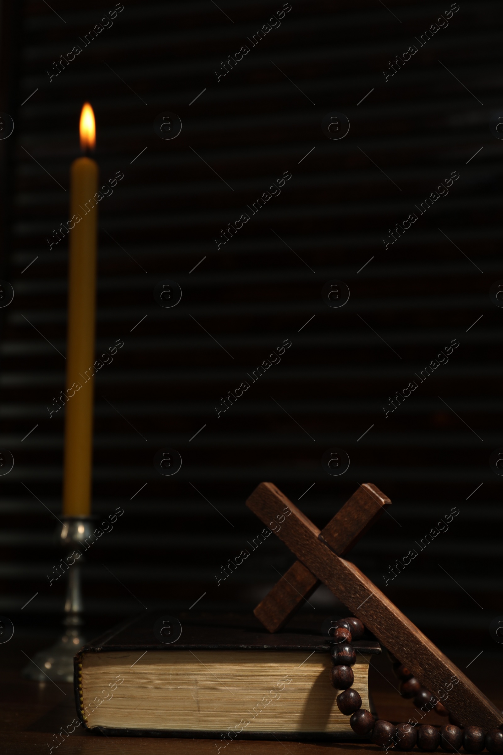 Photo of Church candle, Bible, cross and rosary beads on wooden table