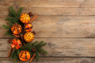 Flat lay composition with pomander balls made of fresh tangerines and orange on wooden table. Space for text