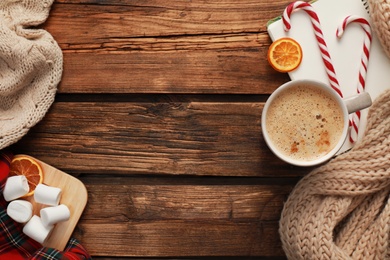 Photo of Flat lay composition with cup of coffee and sweets on wooden table, space for text. Cozy winter