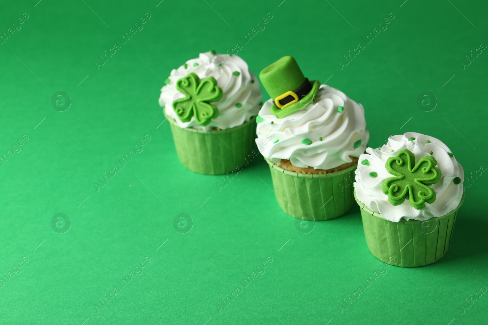 Photo of St. Patrick's day party. Tasty festively decorated cupcakes on green table. Space for text