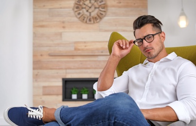 Photo of Portrait of handsome young man sitting in armchair indoors