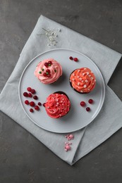 Delicious cupcakes with pink cream and berries on grey table, top view