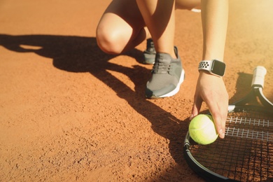 Photo of Woman wearing modern smart watch during training on tennis court, closeup