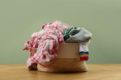 Photo of Laundry basket with clothes near light green wall