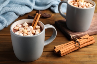 Delicious hot drink with cinnamon and marshmallows on wooden table